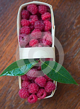 Macro raspberries in a basket with green leaf