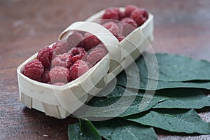 Macro raspberries in a basket with leaf