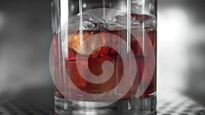 Macro shoot of Red martini pouring in a glass full with a ice cubes. Martini fill a glass with ice. Making of cocktails