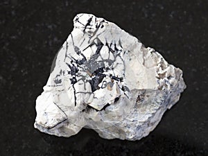 Ilmenite black crystals on raw stone on dark photo