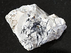 Ilmenite black crystals on rough stone on dark photo