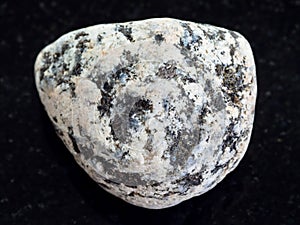 pebble of Diorite stone on dark background photo