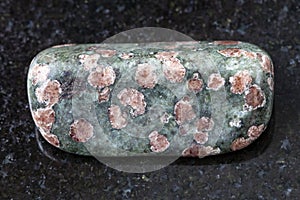 polished Eclogite gemstone on dark background photo