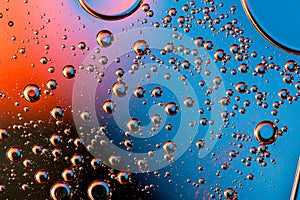 Macro shot of backlit liquid with small bubbles in it over colored background