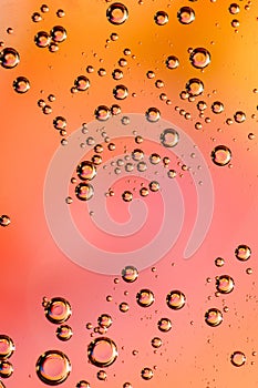 Macro shot of backlit liquid with small bubbles in it over colored background