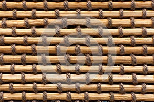 Macro shot of a bamboo mat held together with cords woven between the sticks