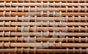 Macro shot of a bamboo mat held together with cords woven between the sticks