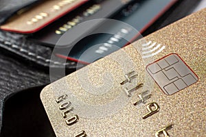 Macro shot of a bank plastic card with a chip, a leather wallet with cards in the background