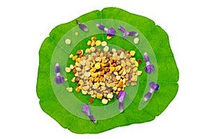 Macro shot of bee pollen on green nasturtium leaf white background. Raw brown, yellow, orange and blue flower pollen