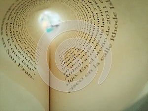 Macro shot of a book page folded into a circle creating a tunnel-like view