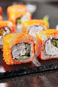 Macro shot of california maki sushi rolls with rice, cream cheese, imitation crab meat, cucumber, orange flying fish caviar and no