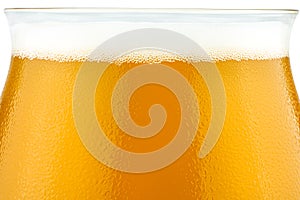 Macro shot of cold beer in a Teku tasting glass filled to full with foam, drops of water on glass, the upper part of the glass is photo