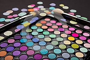 Macro shot of colorful make-up eyeshadow palette with two brushes and confetti