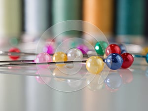 Macro shot of colorful pins with a background of sewing thread