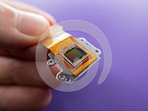 Macro shot of a digital camera Ccd sensor in the hands of a  person on a purple background photo