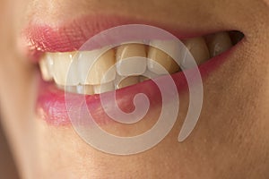 Macro shot of female smile with teeth and pink lipstick photo