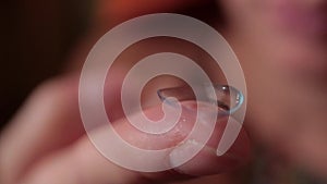 Macro shot of a finger holding a contact lens.