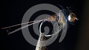 Macro shot of fly fishing lure on a black background, hand made fly for fishing