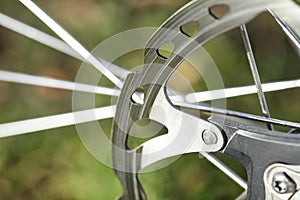 A macro shot of the front bicycle brake disc, visible spokes and a green background.