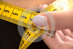 Macro shot Girl measures her waist. measuring tape measure concept