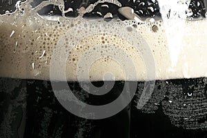 Macro shot glass of Beer with foam bubbles texture background. Craft dark beer flowing foam with sparkling bubbles. Beer foam text
