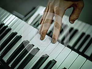 Macro shot hand playing on the synthesizer piano keys