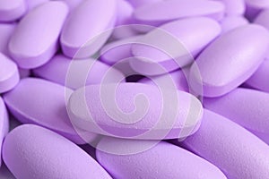 Macro shot of heap of pastel purple oval shaped supplement pills