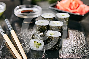 Macro shot of hosomaki sushi with soy sauce on natural black slate plate background with selective focus. Kappa maki sushi roll wi