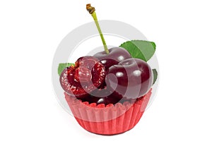 Macro shot of juicy cherry with leaf in red cupcake wrapper isolated on white