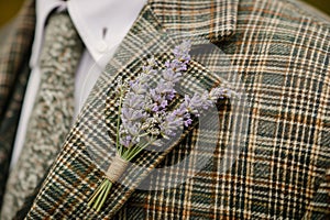 macro shot of a lavender boutonniere on a tweed jacket, outdoors