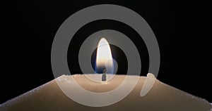 Macro shot of a match lighting a candle on a dark background