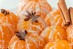 Macro shot of peeled juicy tangerine decorated with star anise spice and cinnamon sticks. Winter holidays atmosphere. Merry