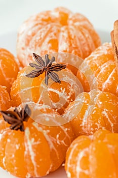 Macro shot of peeled juicy tangerine decorated with star anise spice and cinnamon sticks. Winter holidays atmosphere. Merry