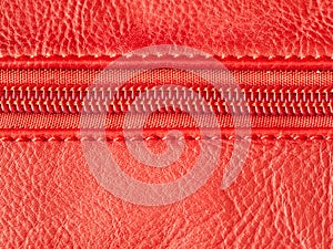 Macro shot of red zipper on leather texture background with stitching. Copyspace