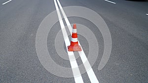 Macro shot of road traffic cones with orange and white stripes standing on street on gray asphalt during road