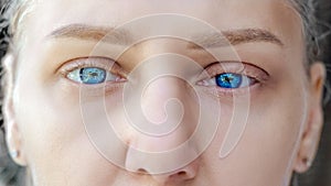 Macro shot of sad blue eyes and swollen eyelids. Young beautiful blonde looks into camera. Eyes of girl with long