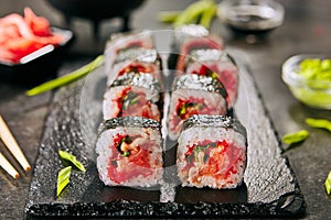 Macro shot of smoked salmon sushi rolls with green onions, flying fish red caviar, spicy sauce and nori on blurred background. Fre