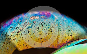 Macro shot of a soap bubble with a bright-colored texture isolated against a black background