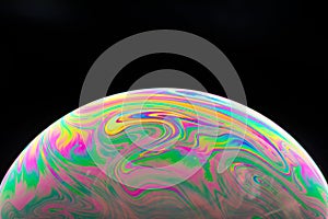 Macro shot of a soap bubble with a bright colorful surface isolated on a black background