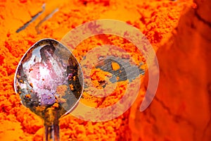 Macro shot of a spoon in a pile of orange pigment in the city of Pushkar