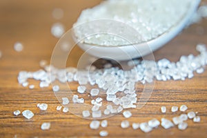 Macro shot of sugar in spoon and sugar crystals in focus on a wooden table. Copy space provided