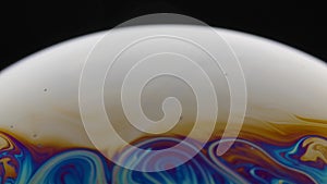 A macro shot of the surface of thin film of soap with rainbow colors creating a beautiful swirling effect. Semicircle of