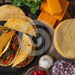 Macro shot view of tasty mexican tacos on rustic wooden table with ingredients for cooking background. Concept of traditional meal