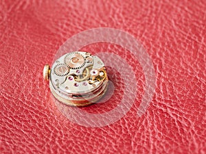 Macro shot of watch mechanism on red leather background. Place for text
