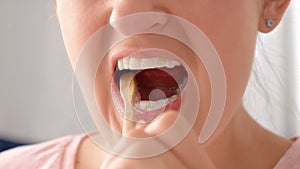 Macro shot of woman brushing her teeth with wooden toothbrush. Concept of teeth health, self checking mouth and oral hygiene