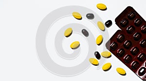Macro shot of yellow oval tablet pills, black tablets pills on white background with creative pattern and black caplets pills