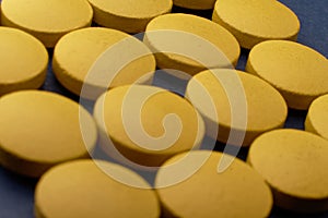 Macro shot of a yellow pill on a blue . It\'s for use in health care and other fields where the color of the pill might