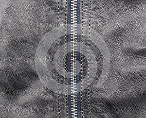 Macro shot of zipper on black leather texture background with stitching. Close-up of black leather material