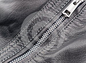 Macro shot of zipper on black leather texture background with stitching. Close-up of black leather material