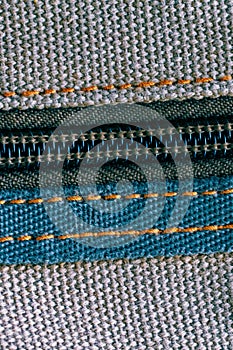 Macro shot of a zipper sewn into woven fabric with visible threads